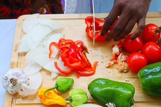 Hands preparing fresh peppers, onions and tomatoes during a Turks and Caicos cooking experience